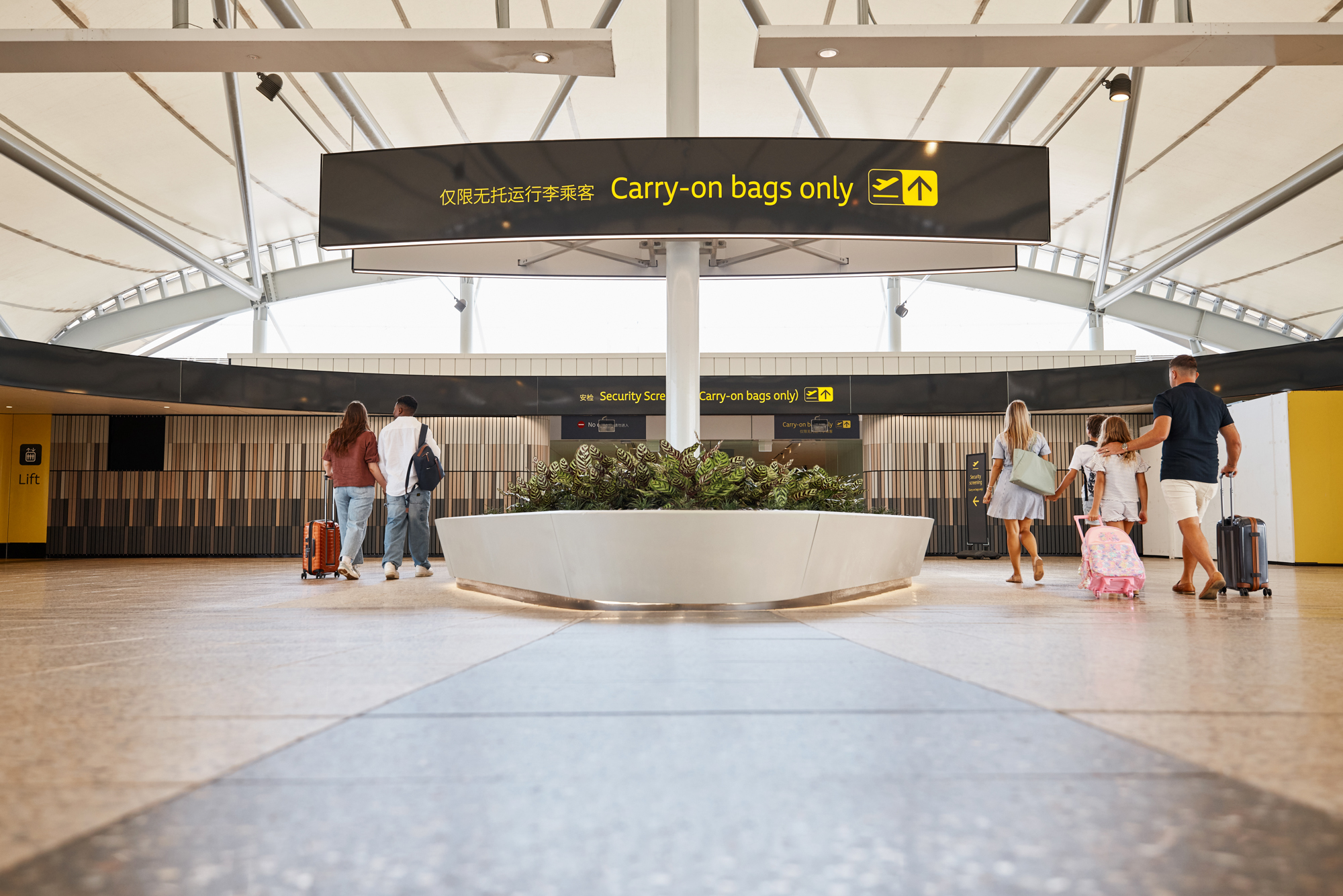 a couple and a family entering the Brisbane Airport Domestic Terminal via the Skywalk